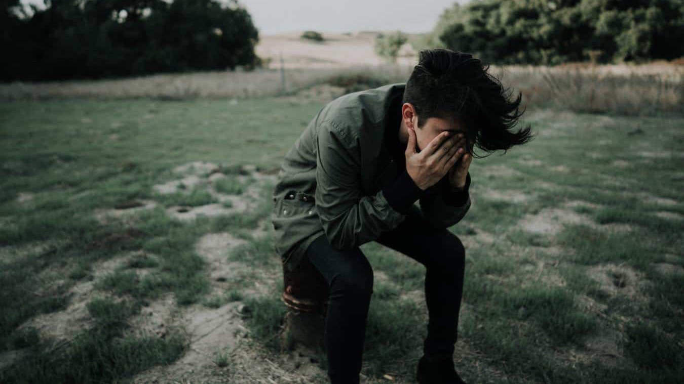 a young person sits dejected with their face in their hands