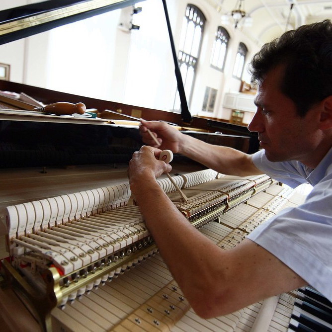 A piano technician examines a piano hammer.