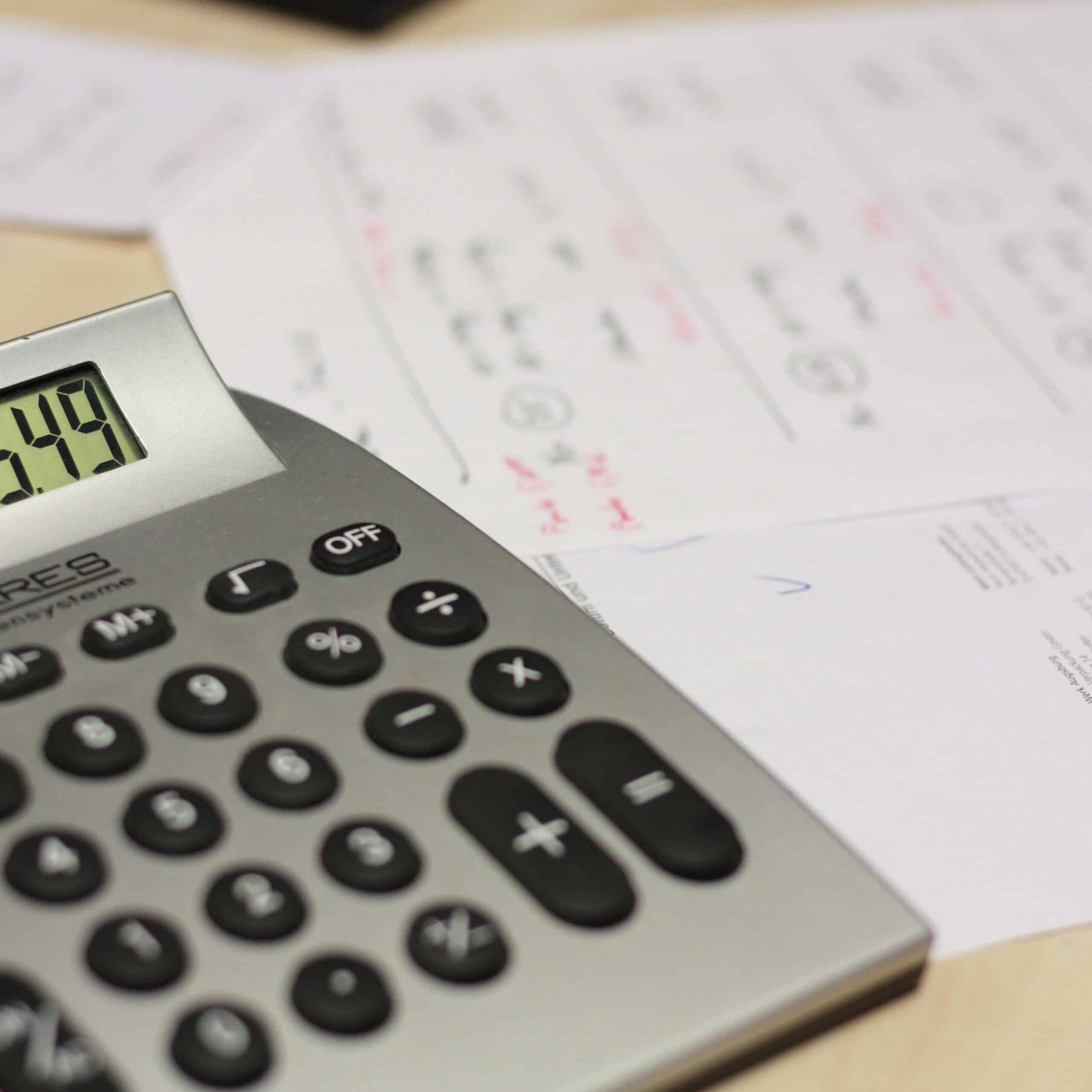 An electronic calculator sits atop a paper with figures written on it